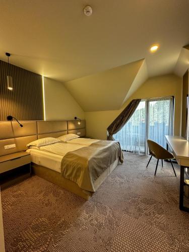 a bedroom with a large bed and a desk and a window at Rarău Retreat in Câmpulung Moldovenesc