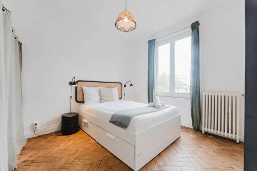 a white bedroom with a bed and a window at La Madeleine -two bedroom apartment in La Madeleine