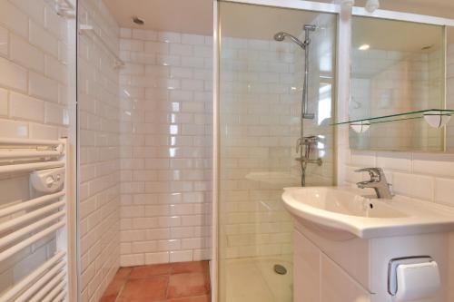 a white bathroom with a sink and a shower at 300m plage - Petite maison avec jardin pour 3 in LʼÉpine