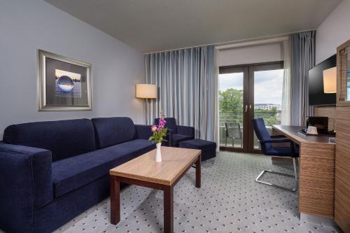 a living room with a blue couch and a table at Maritim Hotel Darmstadt in Darmstadt