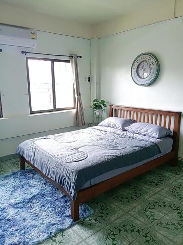 a bedroom with a bed with a blue rug and a window at Come again Coffee and Hostel in Jomtien Beach