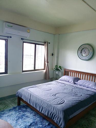 a bedroom with a bed and two windows at Come again Coffee and Hostel in Jomtien Beach