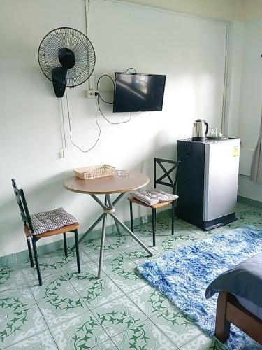 a kitchen with a table and two chairs and a refrigerator at Come again Coffee and Hostel in Jomtien Beach