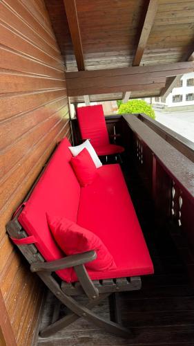 a red bed and two chairs on a balcony at Appartements Schweiberer in Ried im Zillertal