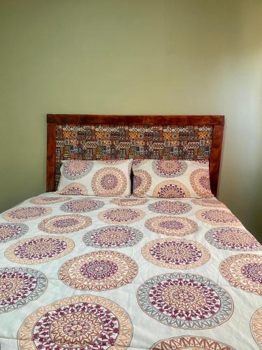 a bed with a quilt and pillows on it at Forest Views Haven - Flat 2 in Solwezi