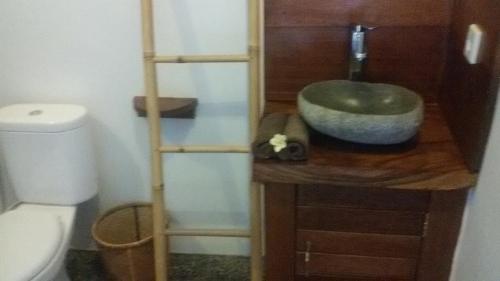 a bathroom with a sink on a wooden counter next to a toilet at Suka's House Bed & Breakfast in Ubud