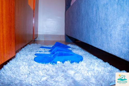 a pair of blue gloves sitting on the floor next to a bed at Nolcare Cozy haven-Kisumu in Kisumu