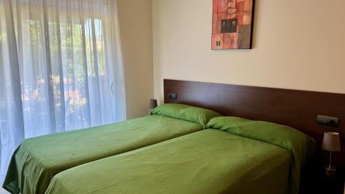 サン・カルラス・デ・ラ・ラーピタにあるGolden Beach Apartament 2 Dormitoris Vista Piscinaのベッドルーム1室(緑のシーツが敷かれたベッド1台、窓付)