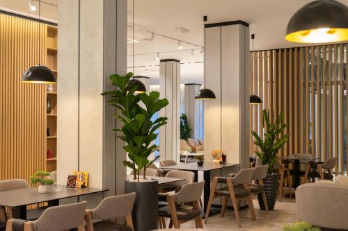a restaurant with tables and chairs and plants at Hotel Vojvodina in Zrenjanin