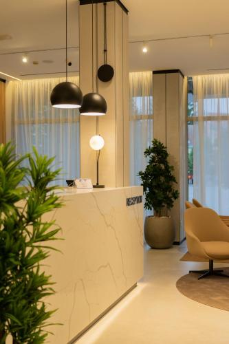 an office lobby with a reception counter and potted plants at Hotel Vojvodina in Zrenjanin