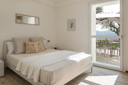 a white bedroom with a bed and a sliding glass door at Villa Serena in Finale Ligure