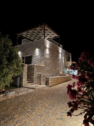 a stone building with lights on it at night at Armenopetra View Gerolimenas in Gerolimenas