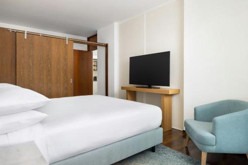 a bedroom with a bed and a chair and a television at Marriott Residences Salgados Resort, Algarve in Albufeira