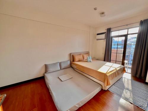 a bedroom with a bed and a couch and a window at 3 Bedroom Spacious Davao Condo in Davao City