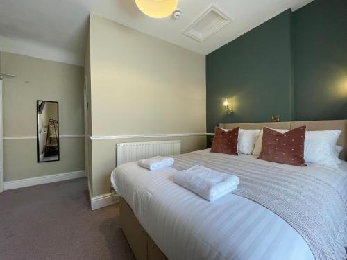a bedroom with a large white bed with red pillows at Wedgwood Hotel, Seascape Room in Llandudno