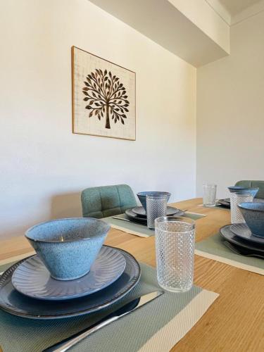 a dining room table with blue bowls and plates on it at Apartamento Brisa Vicentina- Odeceixe in Odeceixe