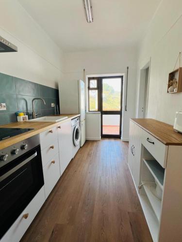 a kitchen with white cabinets and a wooden floor at Apartamento Brisa Vicentina- Odeceixe in Odeceixe
