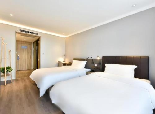two beds in a hotel room with white sheets at Hanting Premium Hotel Beijing Daxing Jinxing Bridge Xingguang Film and Television City in Beijing