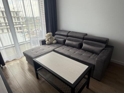 a teddy bear sitting on a couch in a living room at TuWypoczywam - Apartament 58 1C Sianożęty z klimatyzacja i miejscem na dachu in Sianozety