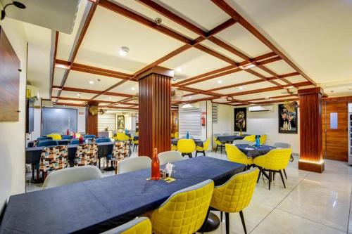 a dining room with blue tables and yellow chairs at Airport Le Premier, New Delhi in New Delhi