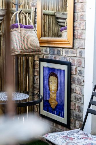 a painting of a boy on a wall with a table at Earthbound Guest House in Oudtshoorn