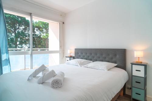 une chambre avec un grand lit blanc avec une fenêtre dans l'établissement Le Nid de Men Er Beleg - Appt proche plage, à Saint-Philibert