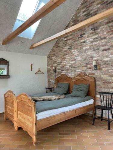 a wooden bed in a room with a brick wall at Koppes Mølle B&B - naturnær overnatning in Borup