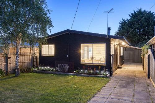 a black house with flowers in the front yard at The Eighth - Pet Friendly in Rosebud