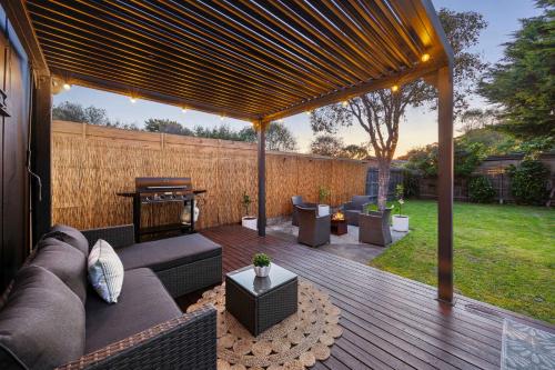 a covered patio with a couch and a grill at The Eighth - Pet Friendly in Rosebud