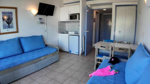un salon avec un canapé bleu et une cuisine dans l'établissement Résidence Goélia Arcadius, à Balaruc-les-Bains