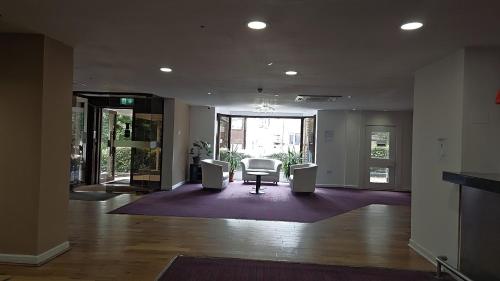 a lobby with a table and chairs in a building at OYO The Luton Hotel in Luton
