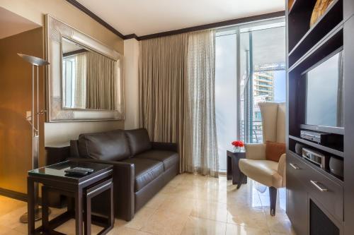 a living room with a leather couch and a television at SBV Luxury Ocean Hotel Suites in Miami Beach