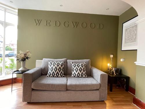 a couch in a living room with a welcome sign on the wall at Wedgwood Hotel - Room 6 in Llandudno