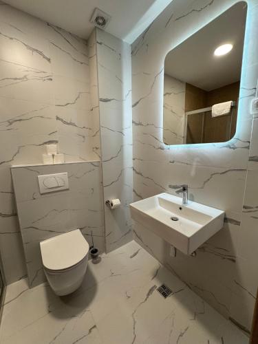 a bathroom with a sink and a toilet and a mirror at Stylish Studio IVSOLE in Budva