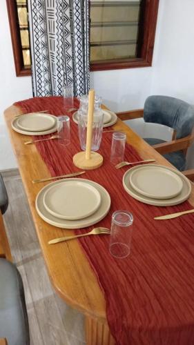 un tavolo di legno con piatti e bicchieri sopra di Lafia Housse a Cotonou