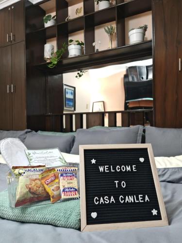 Un cartel de bienvenida a casa con cámara en una cama. en Cozy Condo in Baguio, en Baguio
