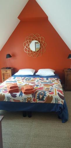 a bedroom with a bed with an orange wall at La Chouetterie in Binic