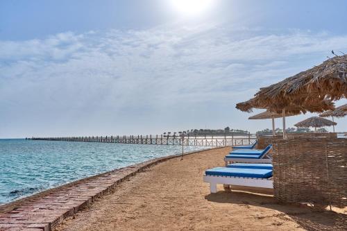 a row of beach chairs with umbrellas and the ocean at Hotel Sultan Bey Resort in Hurghada