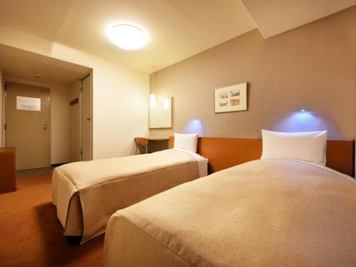 ein Hotelzimmer mit 2 Betten in einem Zimmer in der Unterkunft Morioka City Hotel in Morioka