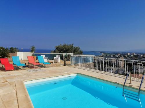 une piscine avec des chaises et une vue sur l'océan dans l'établissement Appartement Vue Mer à Bastia, terrasse et piscine privée., à Bastia