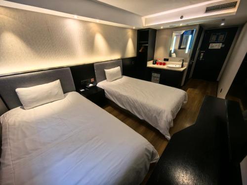 a hotel room with two beds and a mirror at Ibis Beijing Shichahai Gulou Street Subway Station Hotel in Beijing