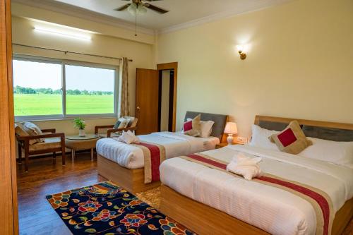a hotel room with two beds and a window at Lumbini Five Elements Hotel in Lumbini
