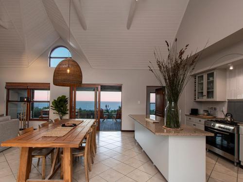 a kitchen with a table and a dining room at Elysian Bay Cottage in Boggomsbaai