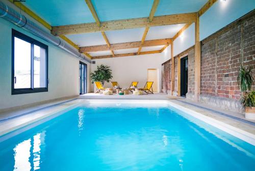 an indoor swimming pool with blue water in a house at L'Escapade d'Acquigny, Piscine, Foot Five, Salle de sport, BabyFoot in Acquigny