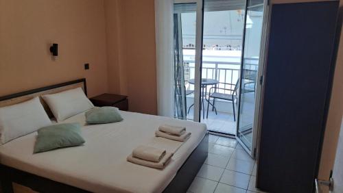 een slaapkamer met een bed met handdoeken en een balkon bij Paulos Apartment in Pefkochori