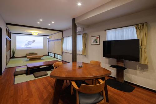 a living room with a table and a flat screen tv at Sakuramachi Villa Projector BBQ Free parking 2 Bed Rooms in Kumamoto