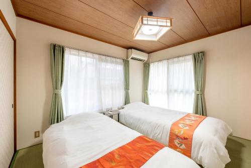 two beds in a room with a window at HIKONE-Step 彦根ステップ 彦根駅徒歩4分 軽自動車用無料駐車場 彦根城徒歩15分 15名まで 戸建貸切 in Hikone