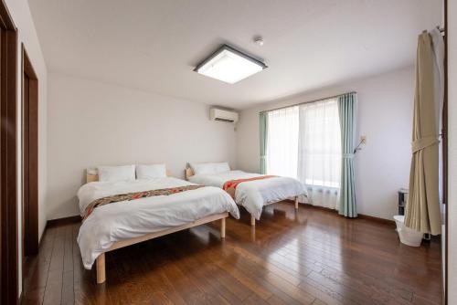 two beds in a room with a window at HIKONE-Step 彦根ステップ 彦根駅徒歩4分 軽自動車用無料駐車場 彦根城徒歩15分 15名まで 戸建貸切 in Hikone