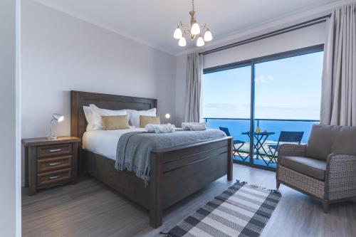 a bedroom with a bed with a view of the ocean at Blue Outlook Retreat by Atlantic Holiday in Água de Pena