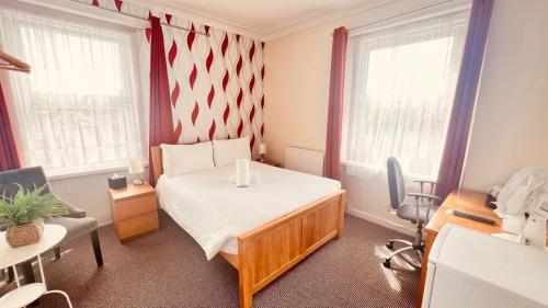 a small room with a bed and two windows at Preston Hotel in Yeovil